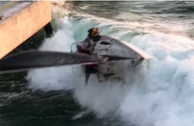 La barca viene scaraventata da un'onda contro il molo e gli uomini dell'equipaggio fuori dalla barca