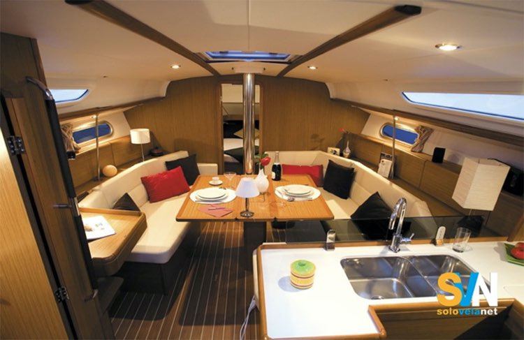 La dinette del Sun Odyssey 39i con divano a C e tavolo centrale; in primo piano la cucina a L