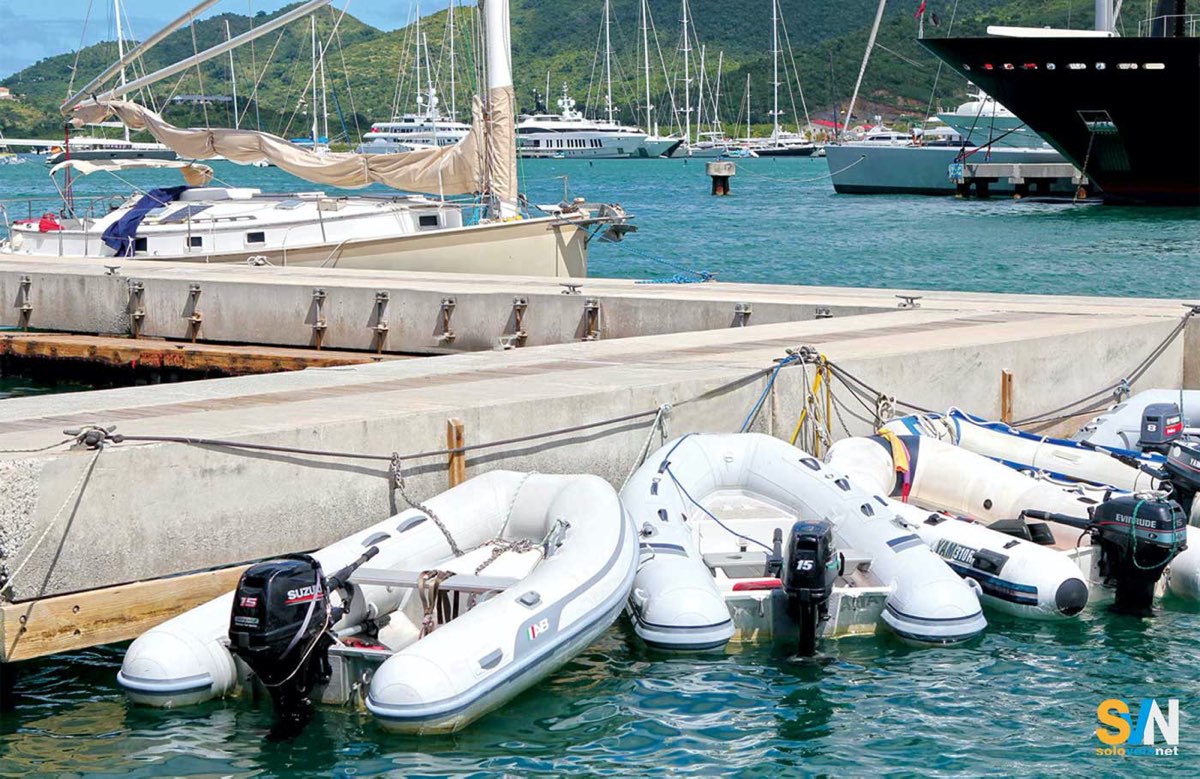 Tender con motori fuoribordo ormeggiati in banchina in un porto turistico, pronti per il rientro a bordo.

